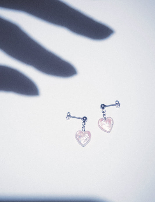 A pair of heart shaped pearl earrings on stainless steel ball studs