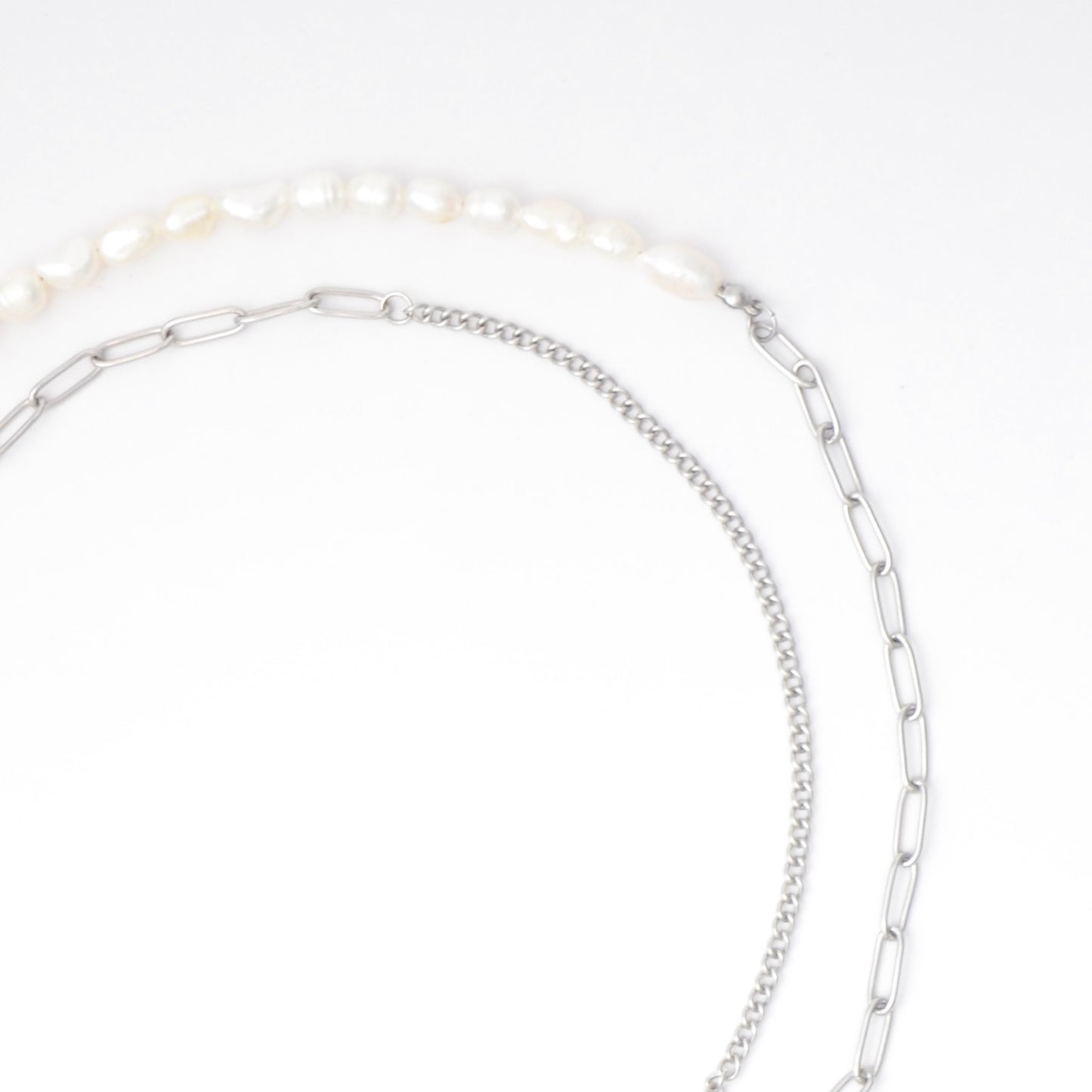 Silver necklace with pearls and textured chains with a toggle clasp and pearl pendant on a white background