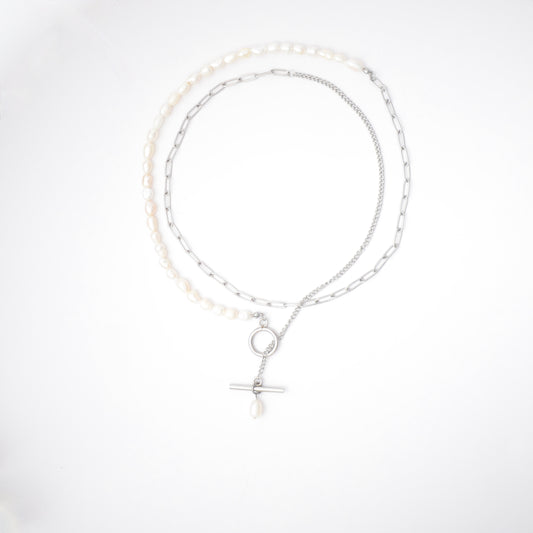 Silver necklace with pearls and textured chains with a toggle clasp and pearl pendant on a white background