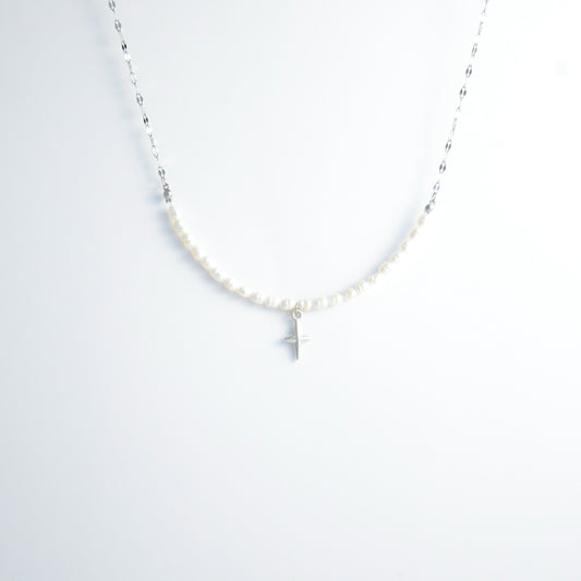 Silver pearl choker necklace with a small north star pendant on a light gray background