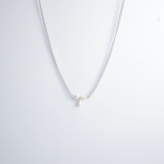 Silver necklace non-tarnish with three pearl beads on a light gray background