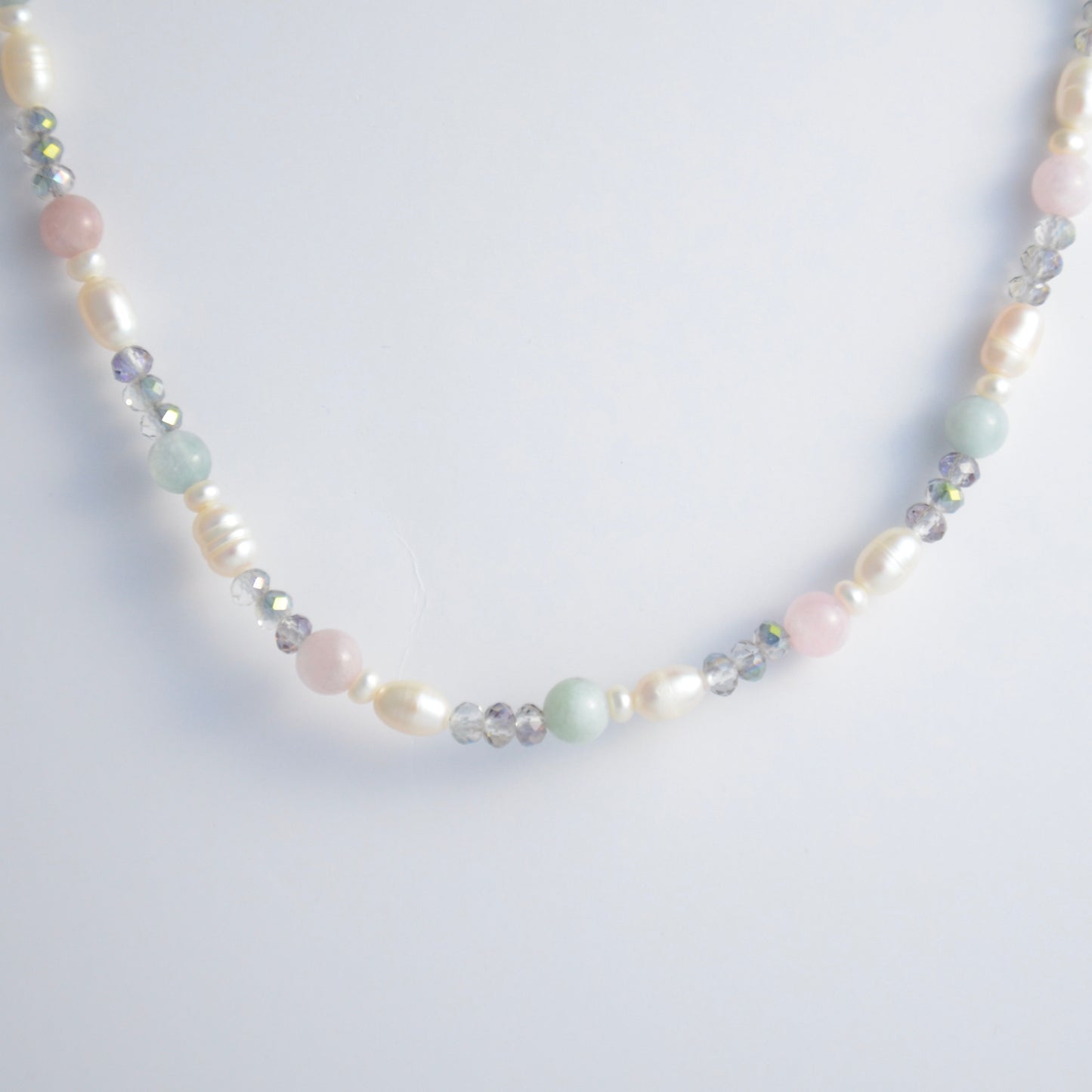 Beaded necklace with pearls and glass beads on a light gray background