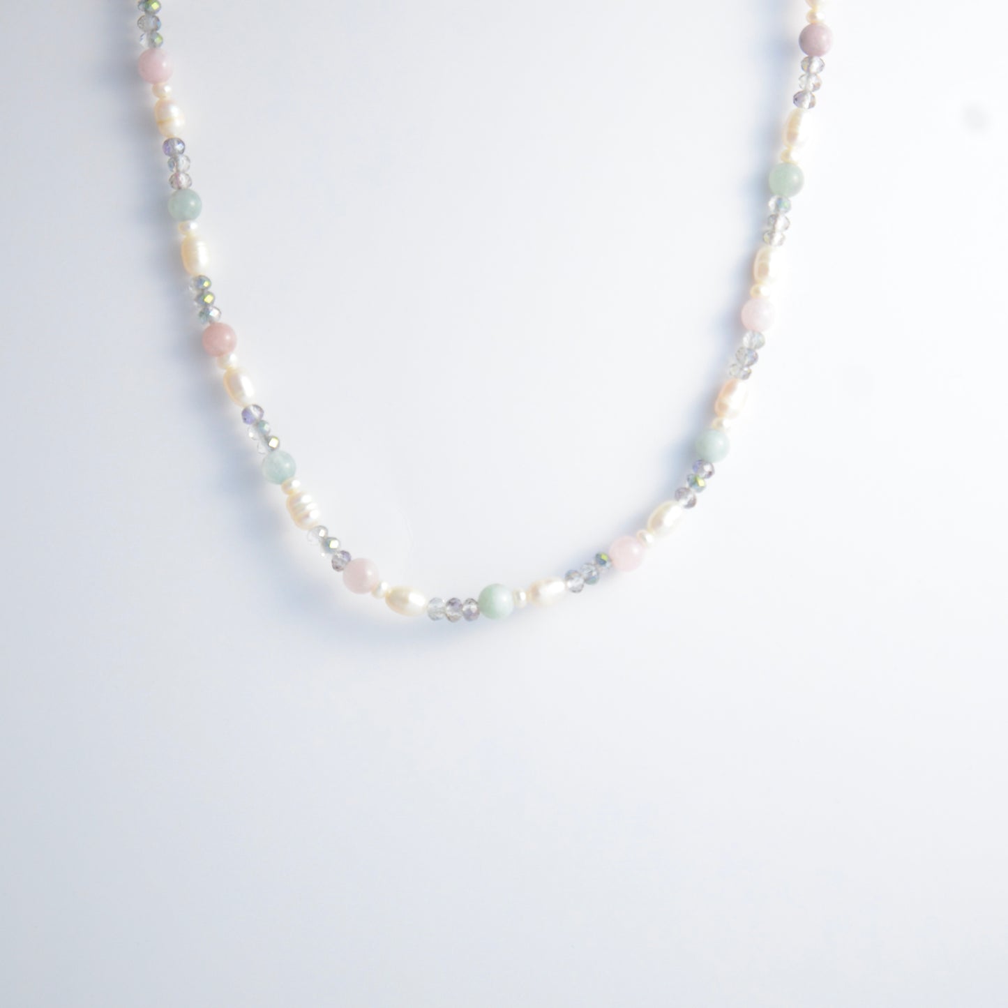Beaded necklace with pearls and glass beads on a light gray background