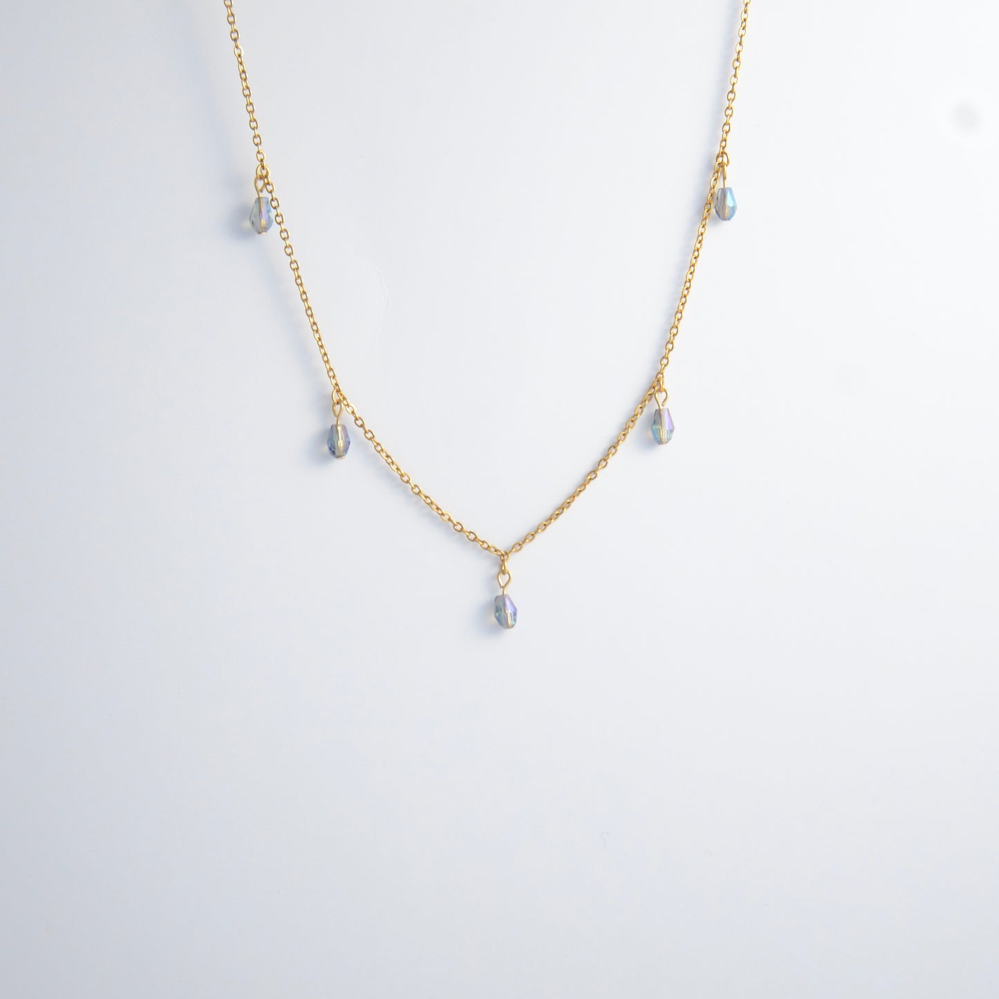 Gold satellite necklace with small purple glass beads on a light gray background
