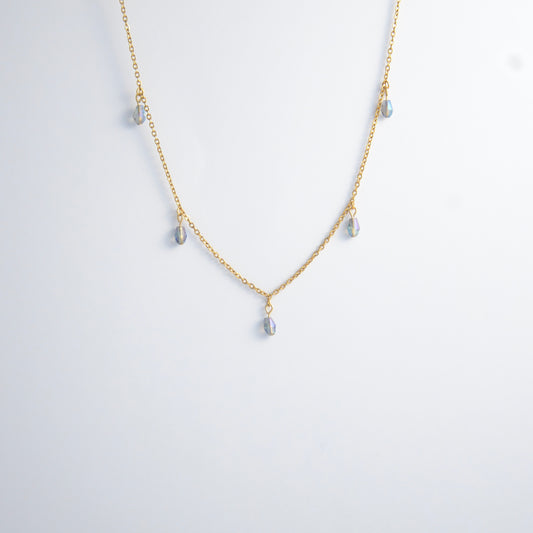 Gold satellite necklace with small purple glass beads on a light gray background