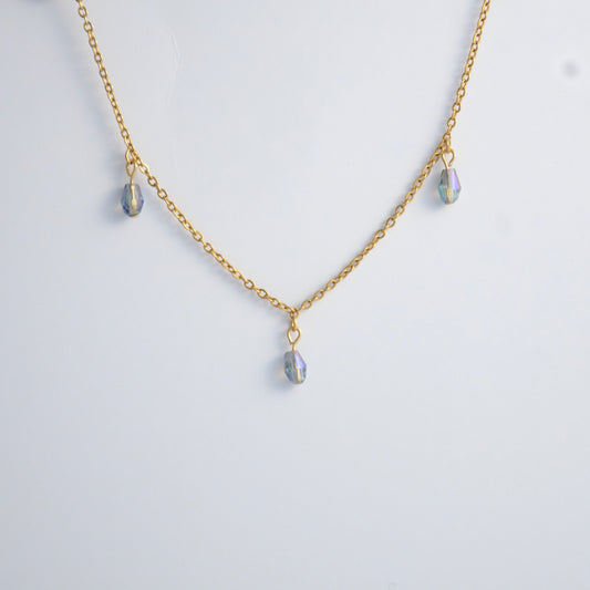 Gold satellite necklace with small purple glass beads on a light gray background