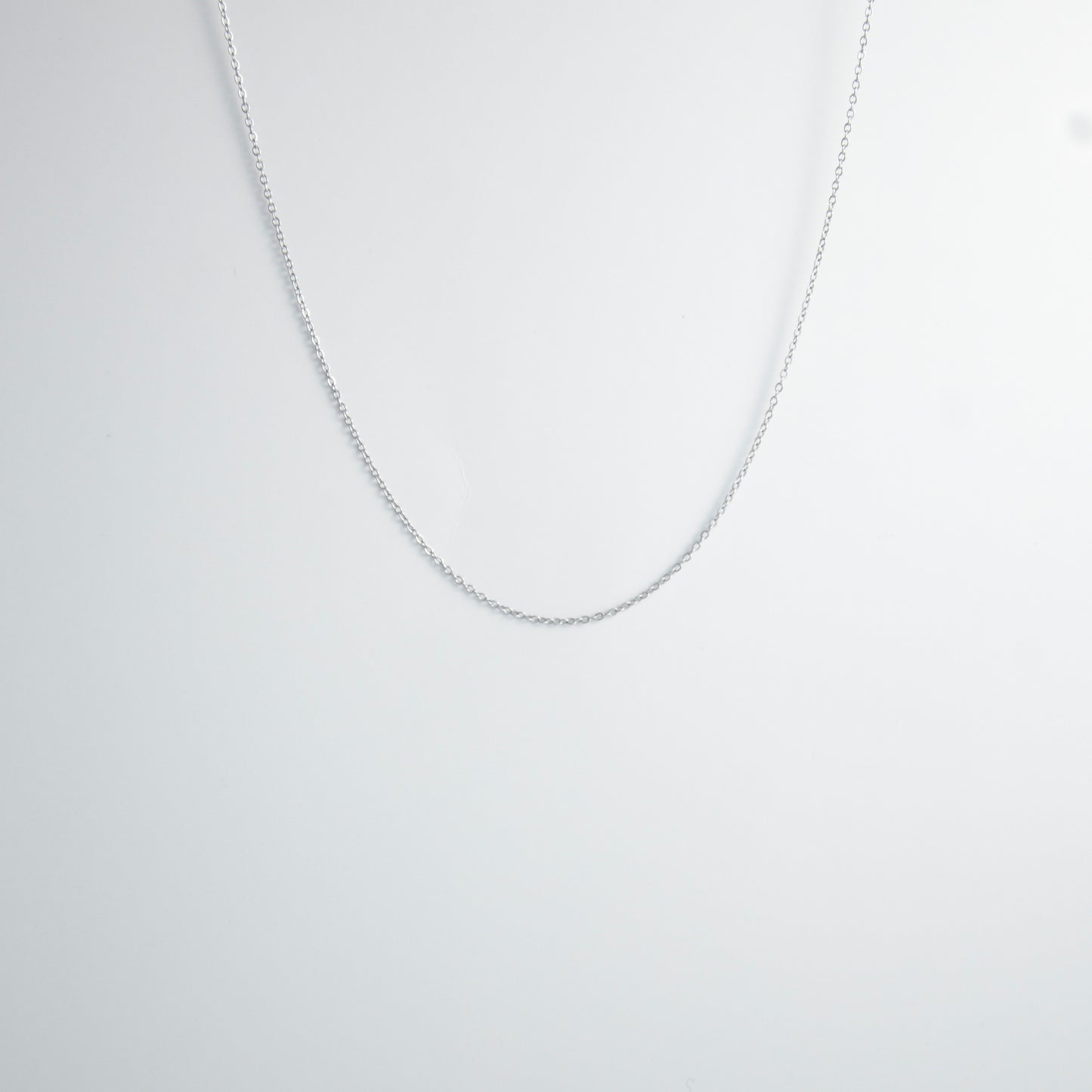 Silver stainless steel dainty chain necklace on a light gray background