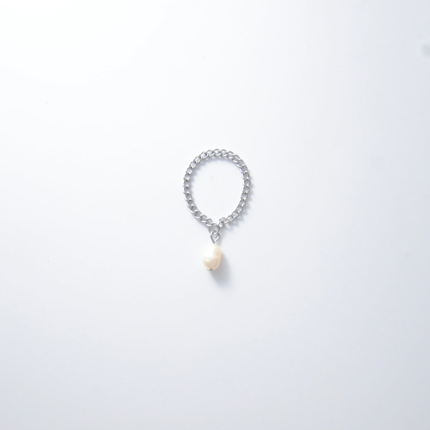 Silver stainless steel curb chain ring with a pearl charm on a white background