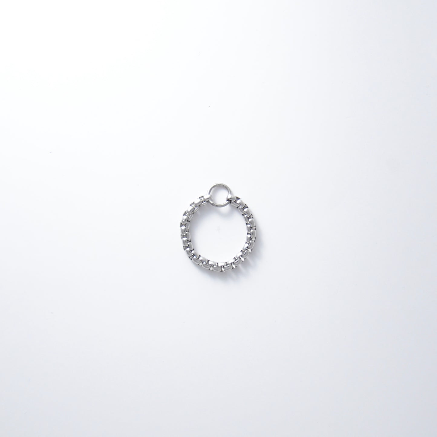 Silver stainless steel box chain ring on a light gray background non-tarnish geometric shape