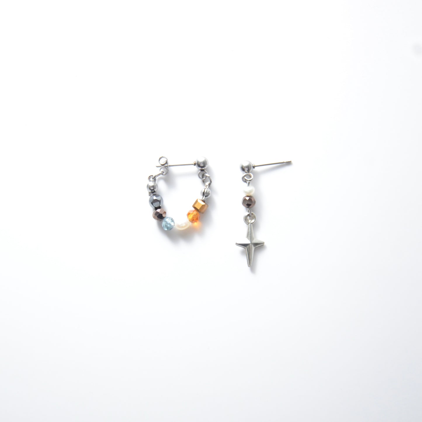 Pair of stainless steel hoop earrings with small beads and drop earrings with star charm on a white background