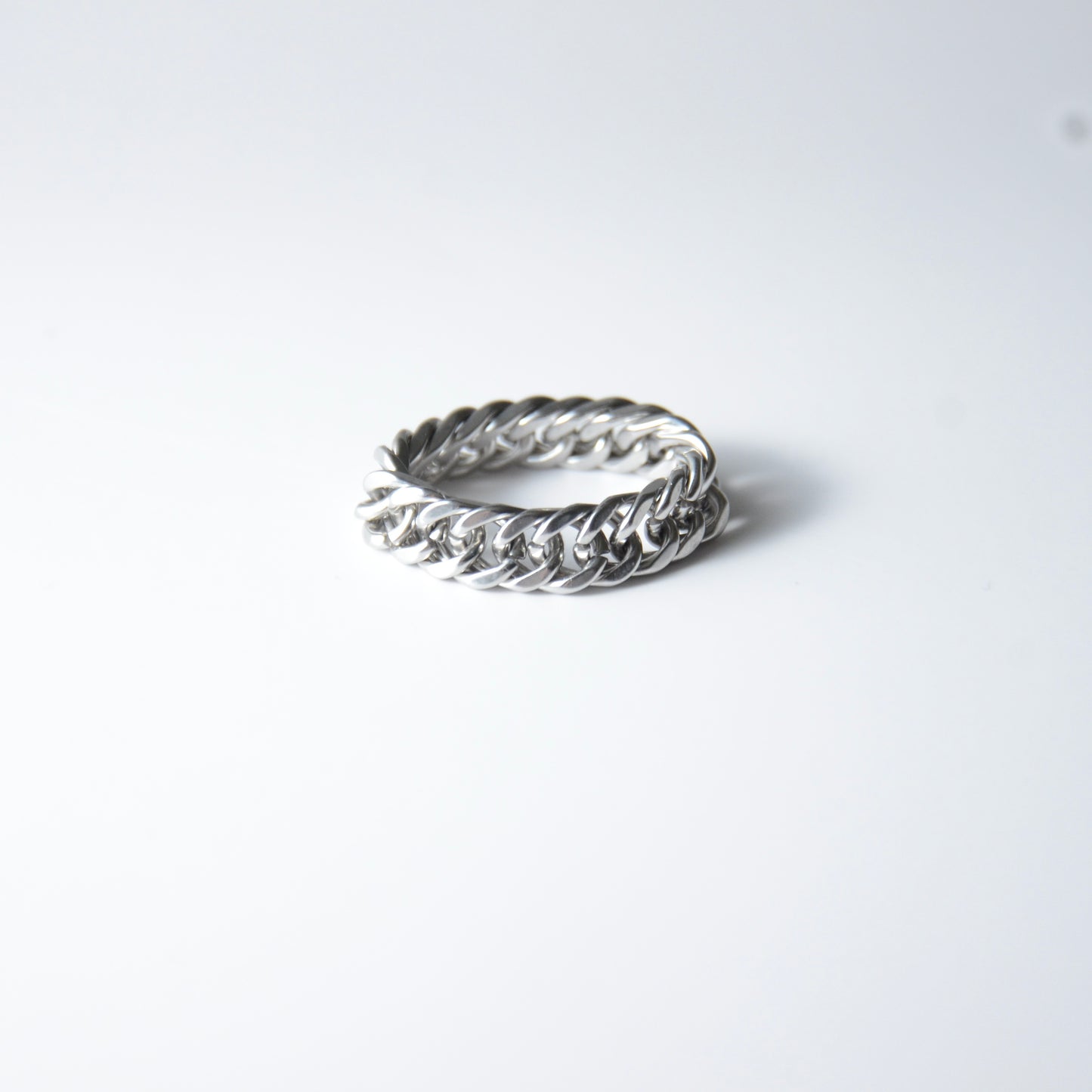 Silver braided cuban chain stainless steel ring on a white background