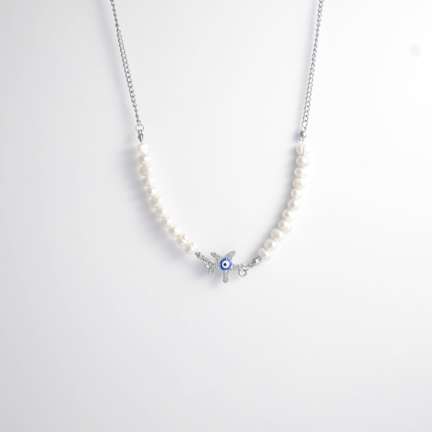 Silver stainless steel pearl choker necklace with a silver star evil eye pendant on a light gray background