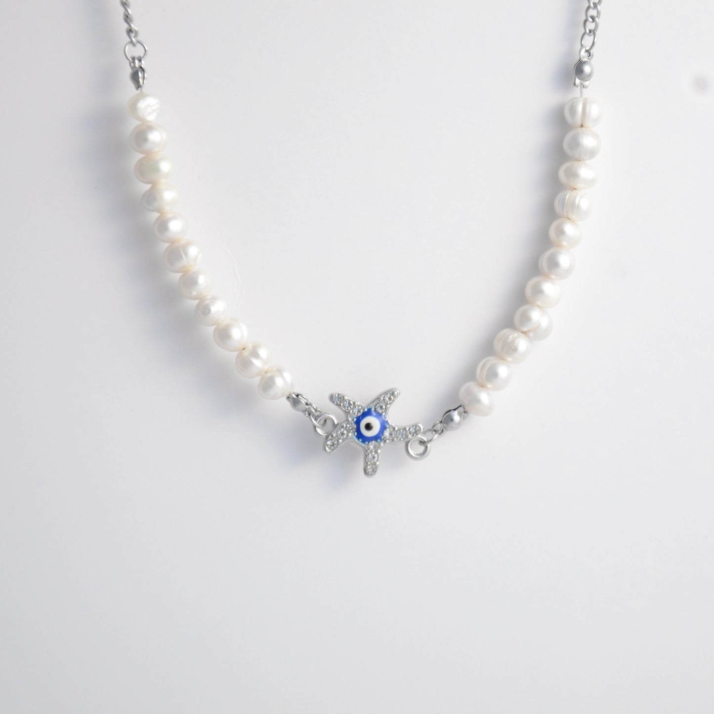 Silver stainless steel pearl choker necklace with a silver star evil eye pendant on a light gray background