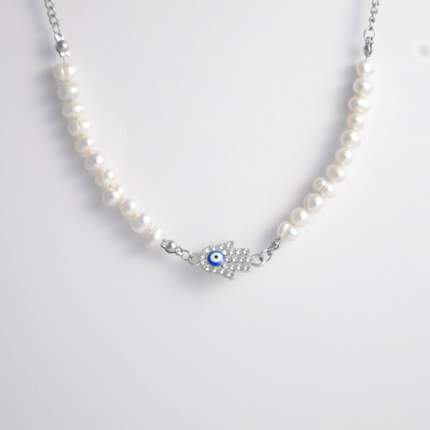 Silver stainless steel pearl choker necklace with a silver hand evil eye pendant on a light gray background