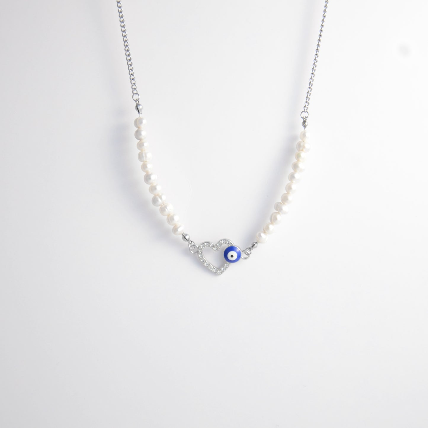 Silver stainless steel pearl choker necklace with a silver heart evil eye pendant on a light gray background