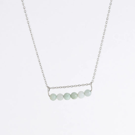 Silver necklace with a pendant made of jade beads on a light gray background