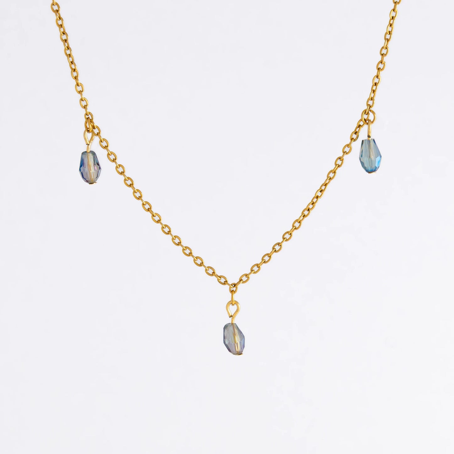 Gold satellite necklace with small purple glass beads on a light gray background