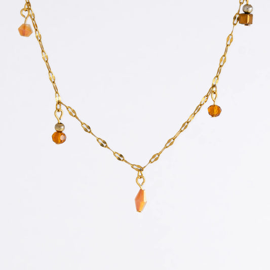 Delicate gold satellite necklace with small orange beads on a light gray background