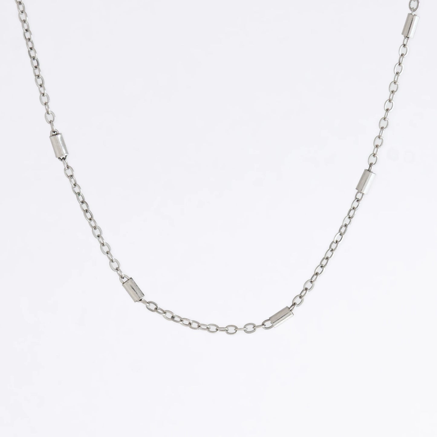 Dainty silver bar link chain for minimalistic fashion or for layering jewelry on a light gray background