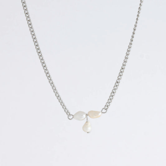 Silver necklace non-tarnish with three pearl beads on a light gray background