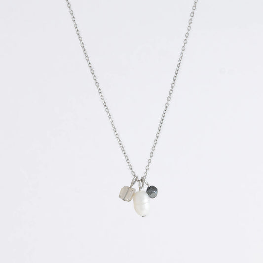 Silver dainty necklace with three small charms made of glass beads and pearls on a white background