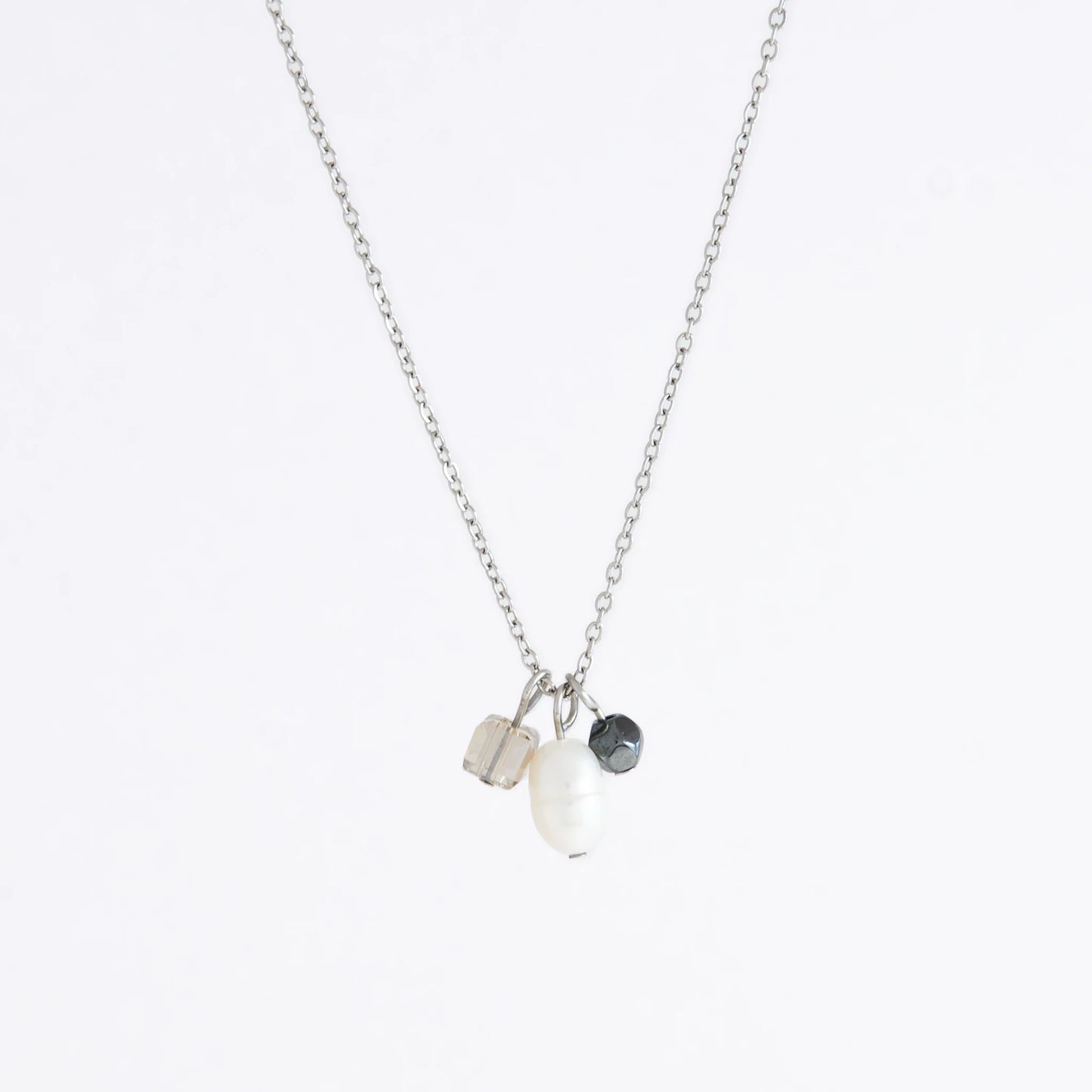 Silver dainty necklace with three small charms made of glass beads and pearls on a white background
