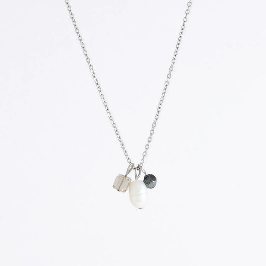 Silver dainty necklace with three small charms made of glass beads and pearls on a white background