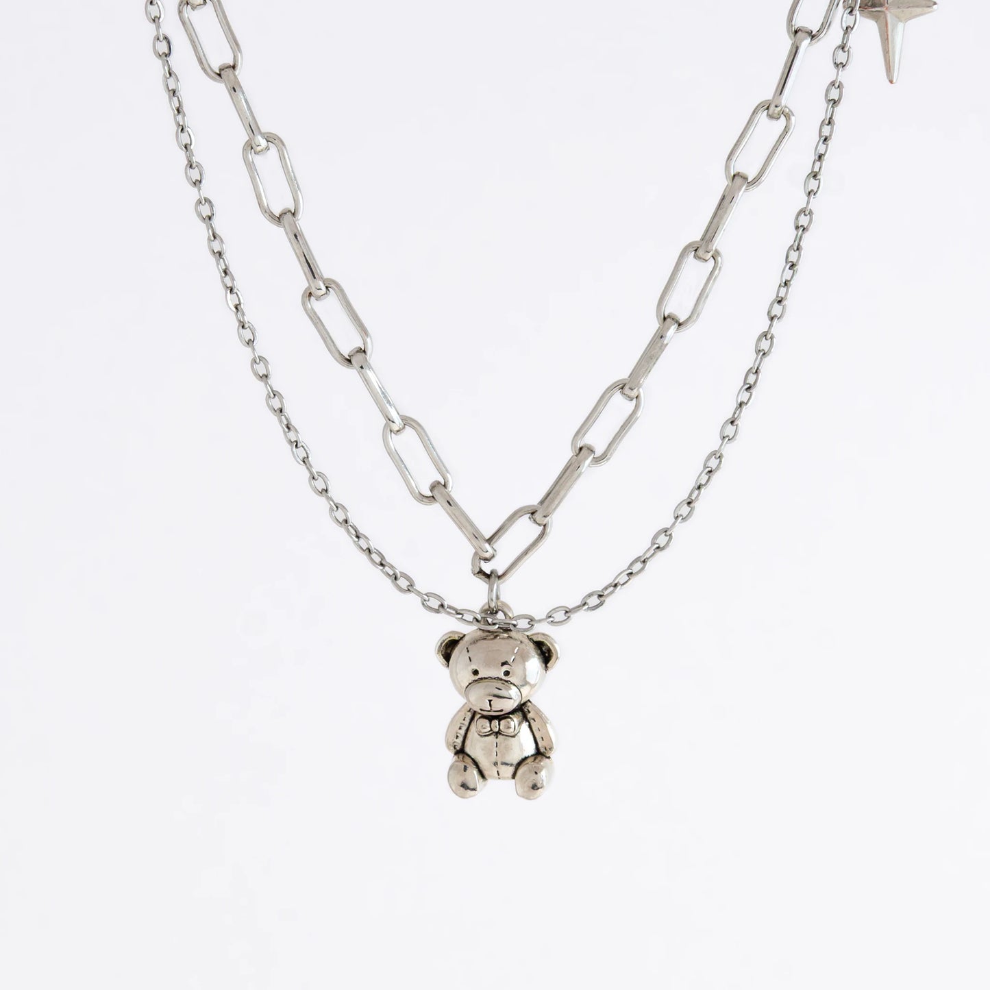 Silver chain necklace with a teddy bear pendant on a white background