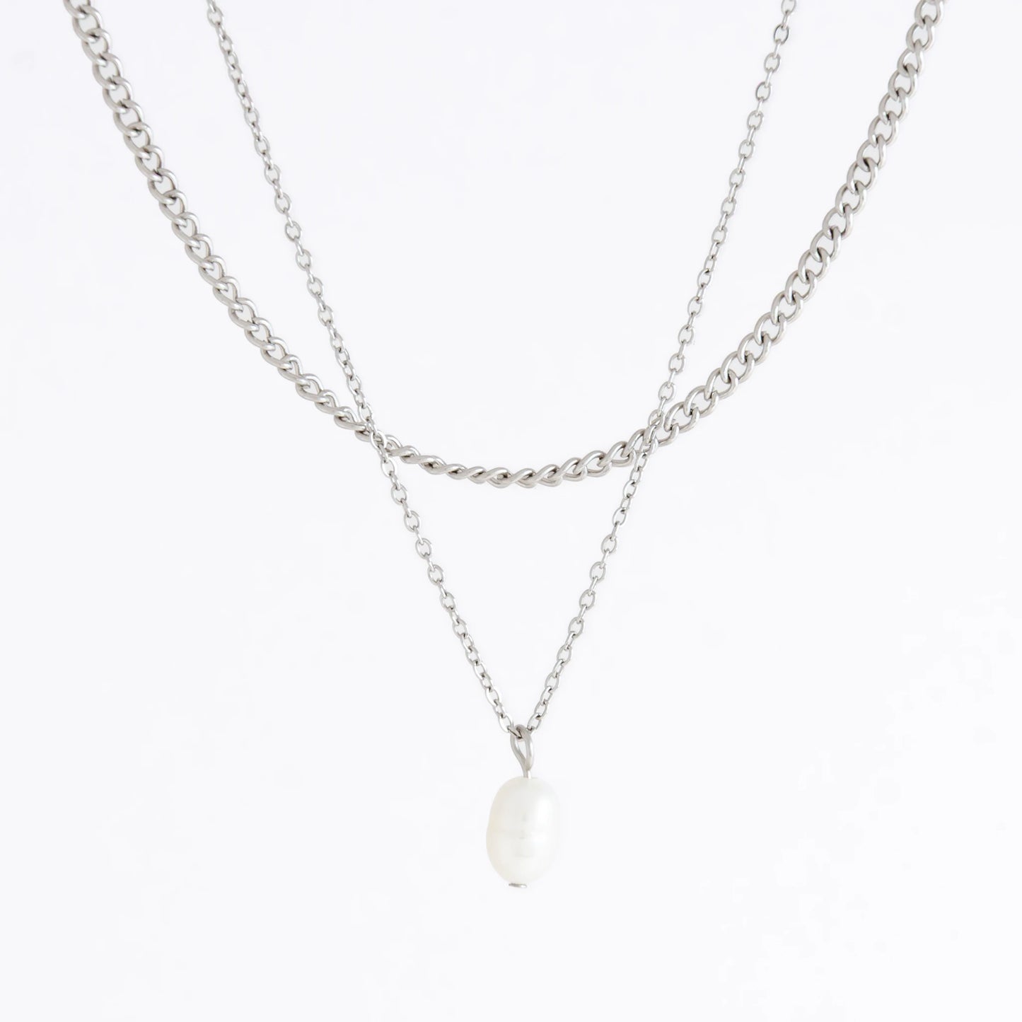 Silver stainless steel layered necklace set with a curb chain and a dainty pearl pendant necklace on a light gray background