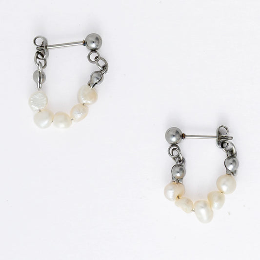 A pair of silver-colored thin pearl hoop earrings, displayed against a white background
