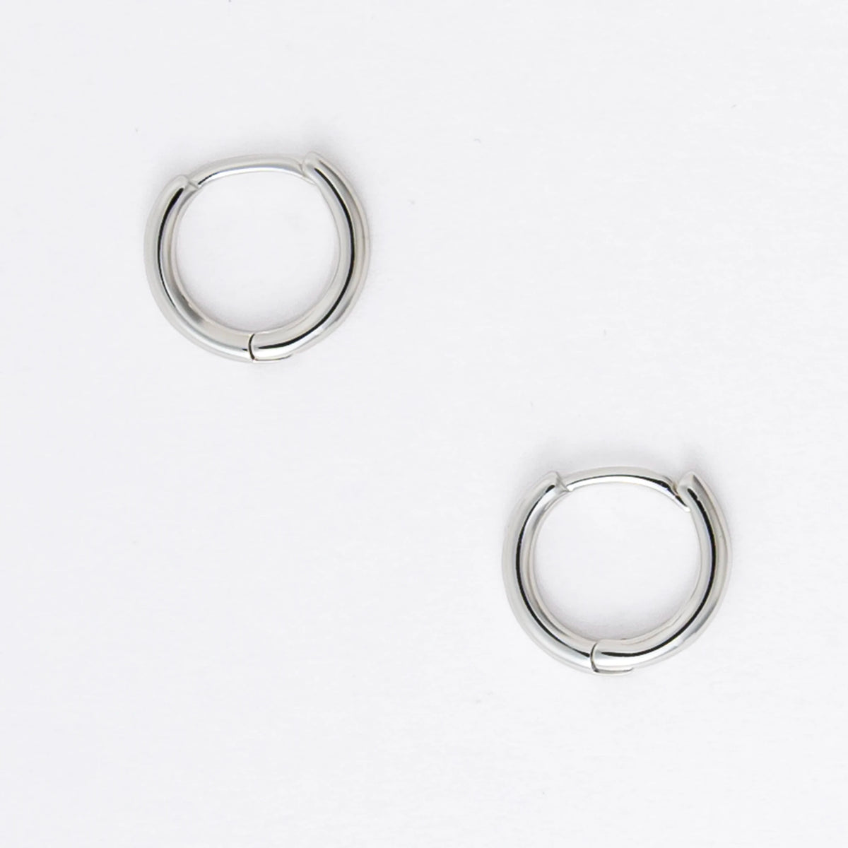 Two silver hoop earrings on a light gray background