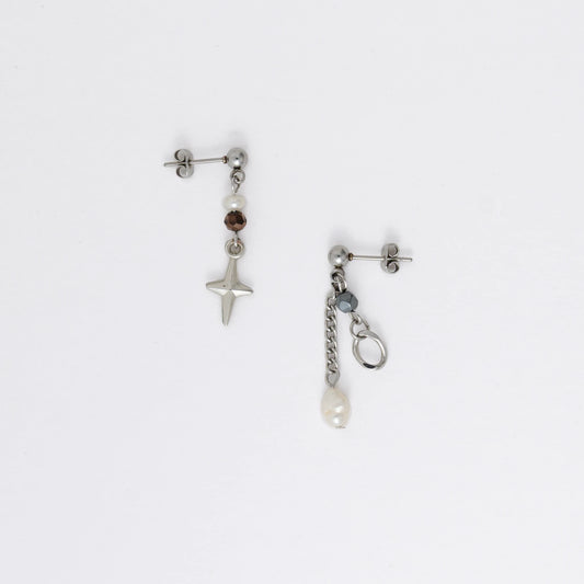 Pair of silver stainless steel ball stud drop earrings with orange and black glass beads and star and pearl charm with unique designs on a white background