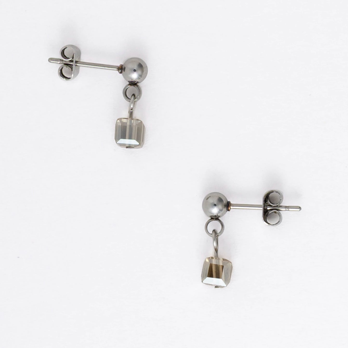 Pair of silver stainless steel ball stud earrings with sugar cube gray glass beads on a white background