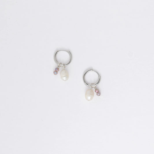 Pair of silver earrings with small pearls on a light gray background