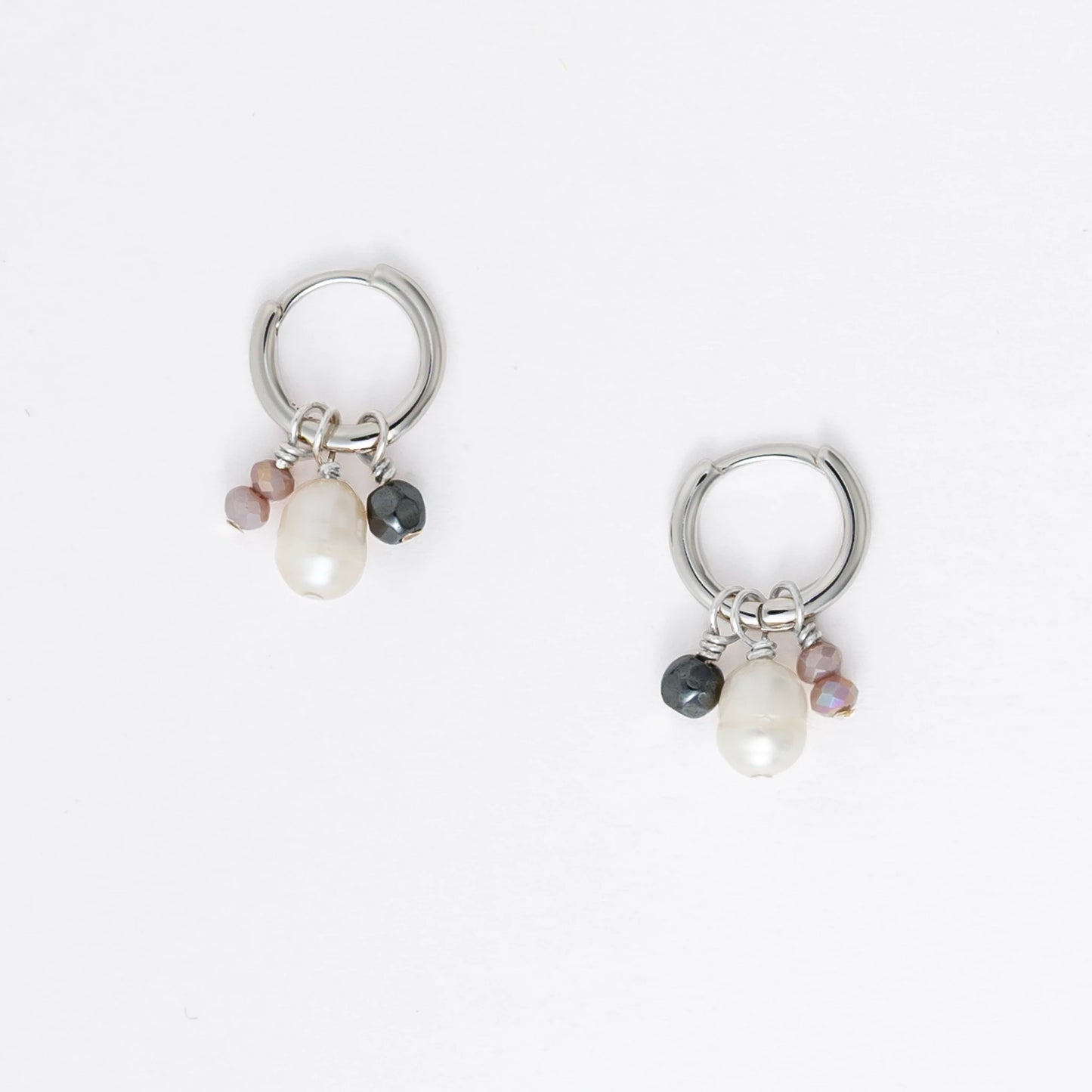 Pair of silver hoop earrings with pearl and gemstone charms on a light gray background