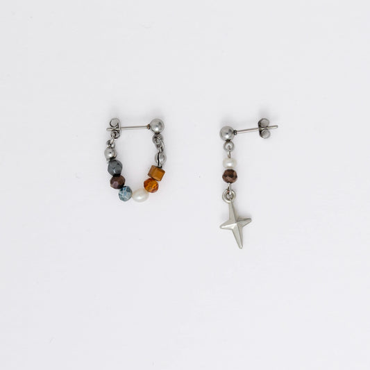 Pair of stainless steel hoop earrings with small beads and drop earrings with star charm on a white background