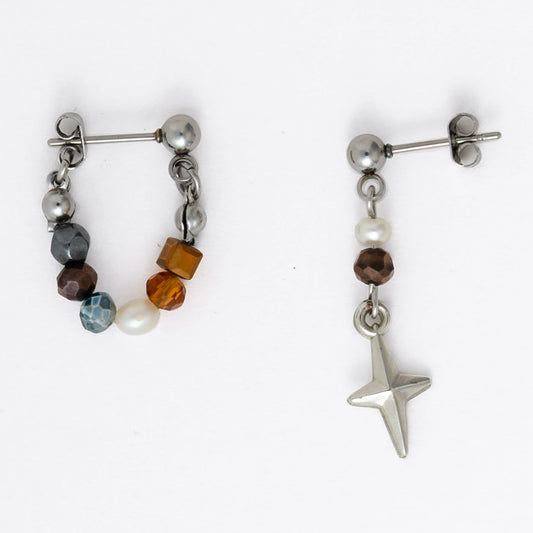 Pair of stainless steel hoop earrings with small beads and drop earrings with star charm on a white background