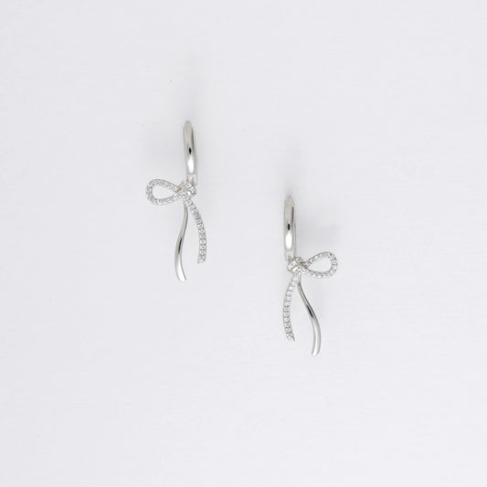 Pair of silver earrings with bow design on a light gray background