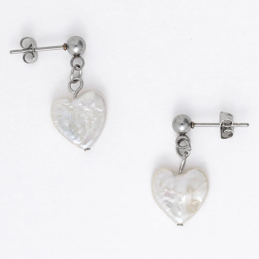 A pair of silver drop earrings featuring heart-shaped white pearls attached to the ends of long silver chains, displayed against a white background.