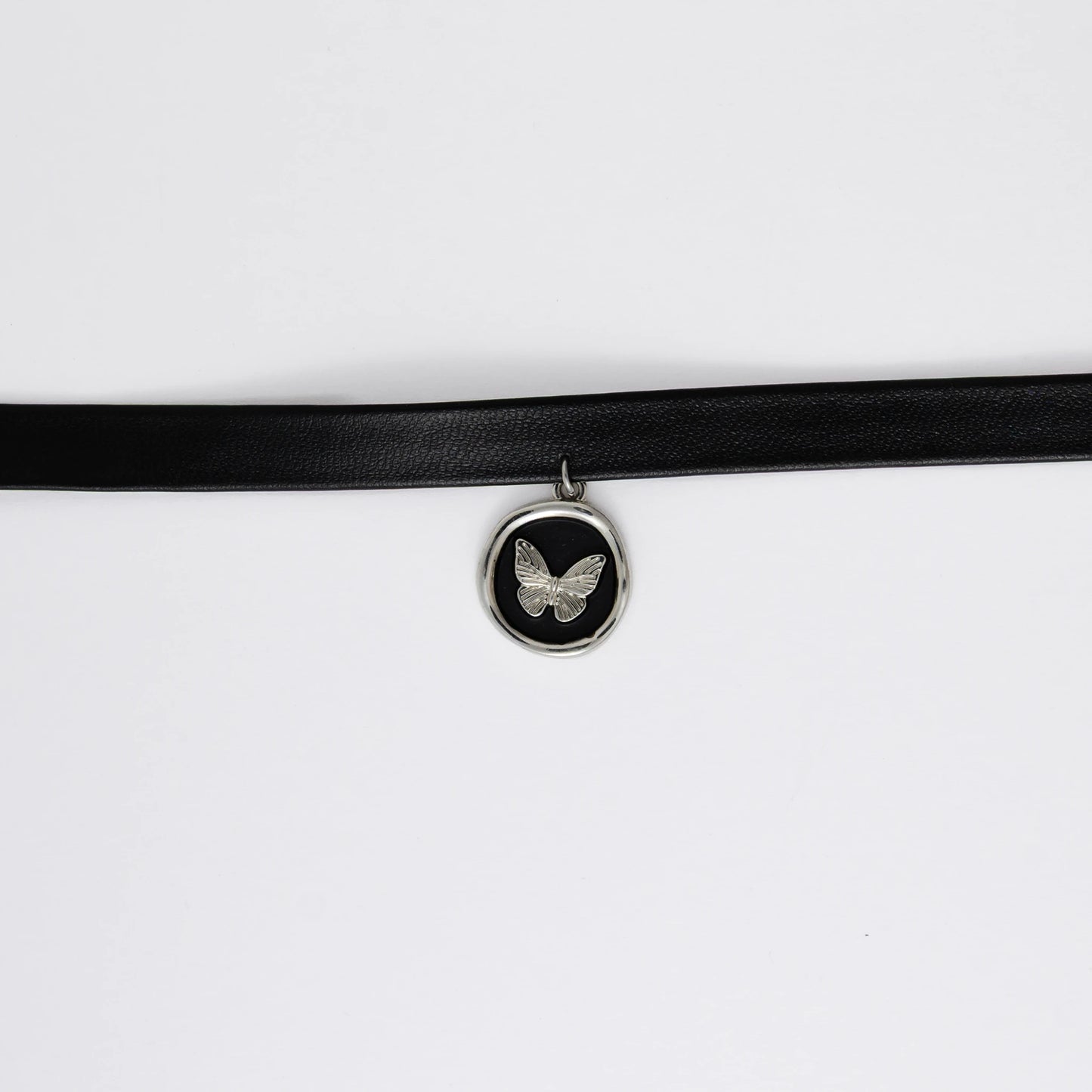 A black leather choker necklace with a central butterfly stamp pendant, displayed against a white background