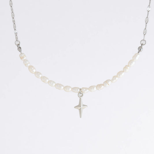 Silver pearl choker necklace with a small north star pendant on a light gray background