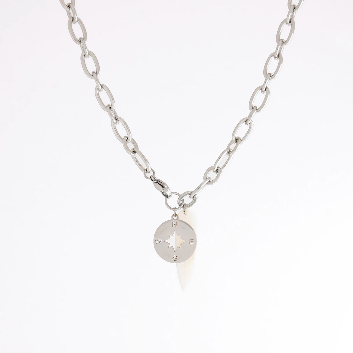 A silver chain necklace featuring a small circular compass pendant with cardinal directions, displayed against a clean white background.