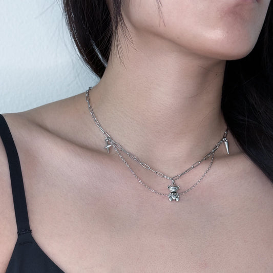 Silver layered necklace with teddy bear charm and star and spike charm worn on a model