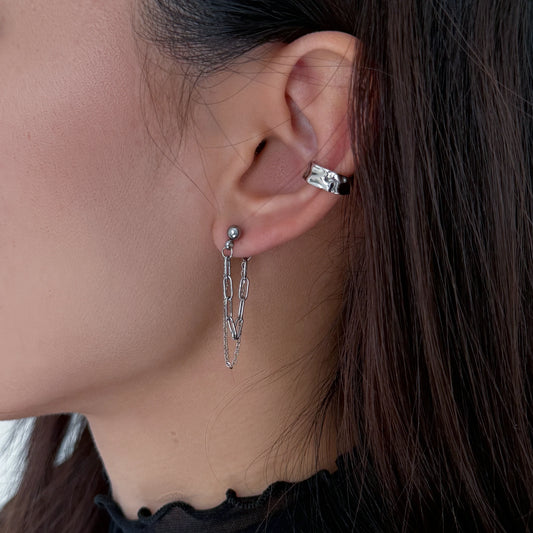 Close-up of an ear wearing a silver hoop earring with a blurred background