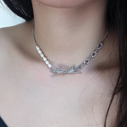 Necklace with pearls and silver winged design on a person's neck
