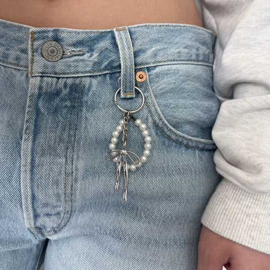 Pearl keychain with silver ribbon on denim jeans