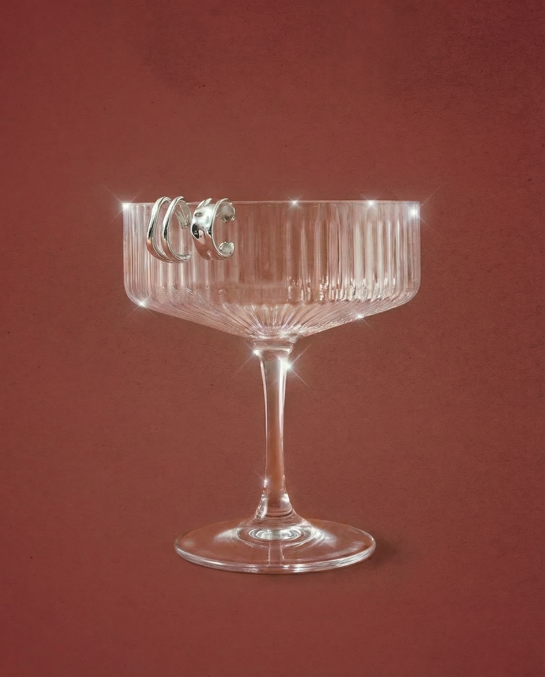 Sterling silver ear cuffs styled on a champagne glass with a red background
