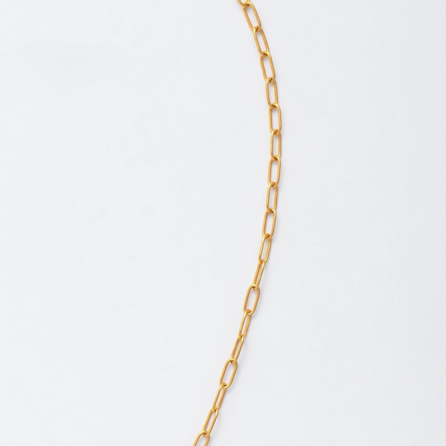 Gold paperclip necklace non-tarnish with a round sun pendant and a pearl on a light gray background