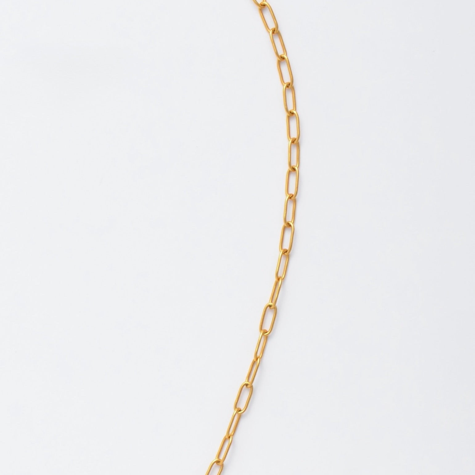 Gold paperclip necklace non-tarnish with a round sun pendant and a pearl on a light gray background