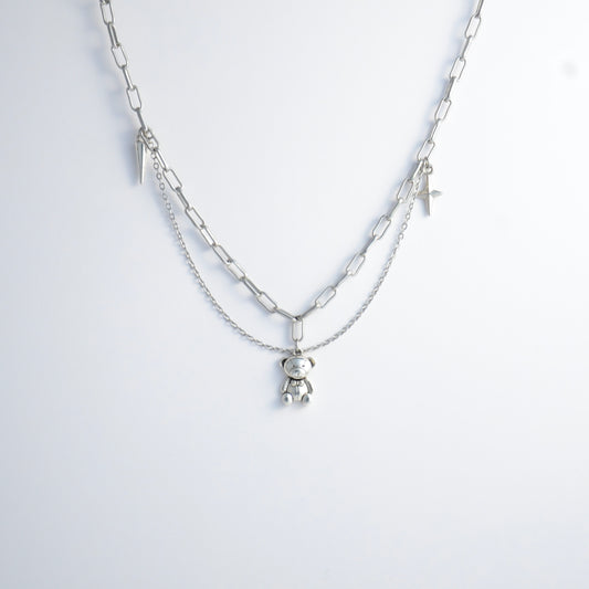 Silver chain charm necklace with a teddy bear pendant on a white background
